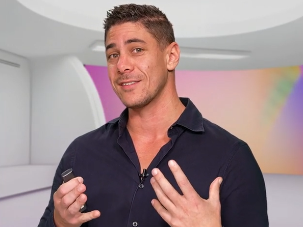 Man in donker overhemd presenteert in een moderne studio met zachte kleurverlichting