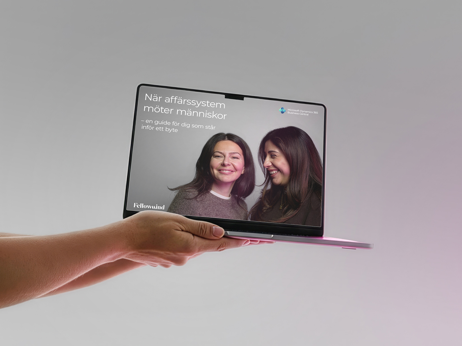 Två händer håller upp en laptop som visar Fellowminds köpguide för Business Central