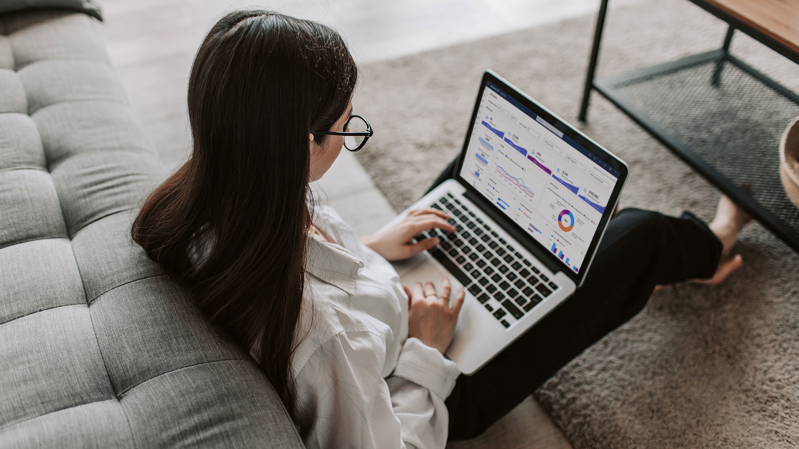 Person arbetar vid laptop med analys- och statistikdashboard i ett hem
